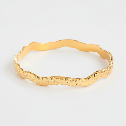 Bracciale rigido ondulato dorato sfondo grigio